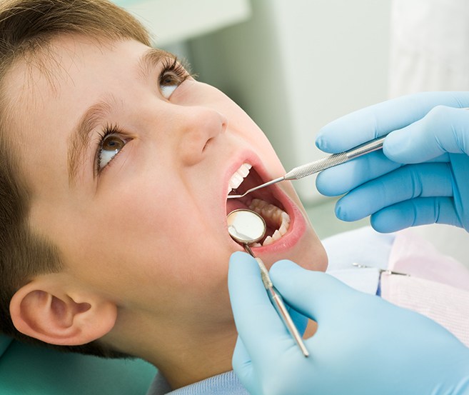 Young boy having his teeth checked during a visit