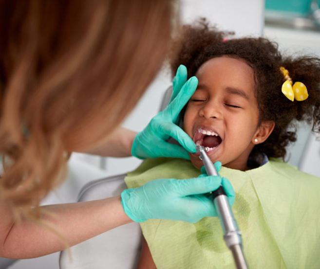 Dentist cleaning child’s teeth