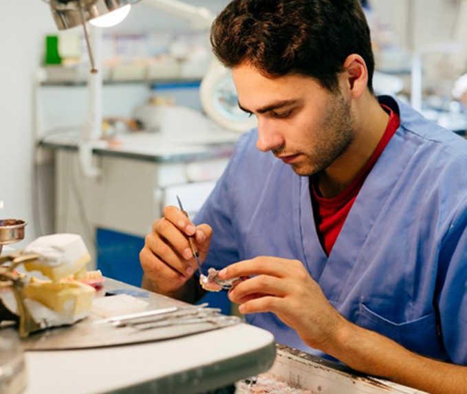 Man meticulously crafting a customized dental crown