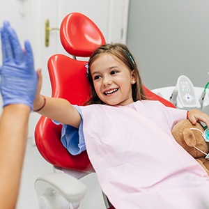 Child smiling while giving dentist high five