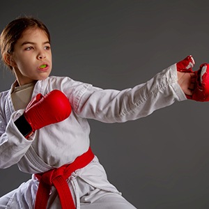 Girl in martial arts uniform and green mouthguard