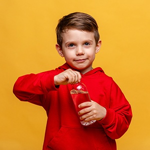 Little boy in red hoodie trying to open water bottle