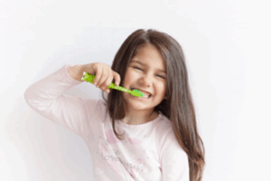 Young child brushing her teeth and smiling