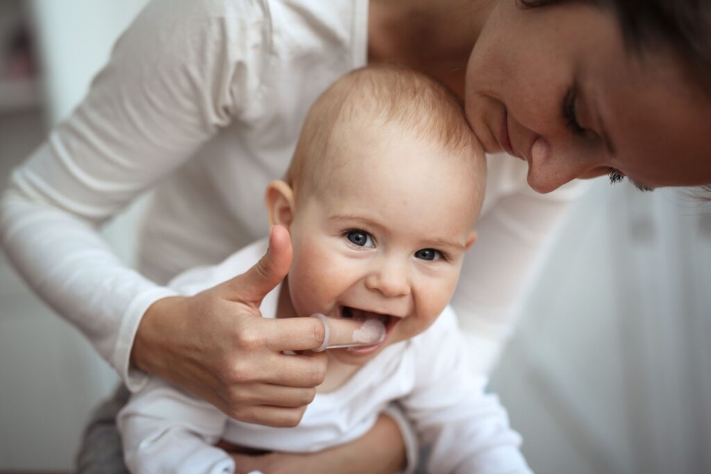 Woman with finger covering touching baby's gums