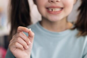 Young girl holding her lost baby tooth